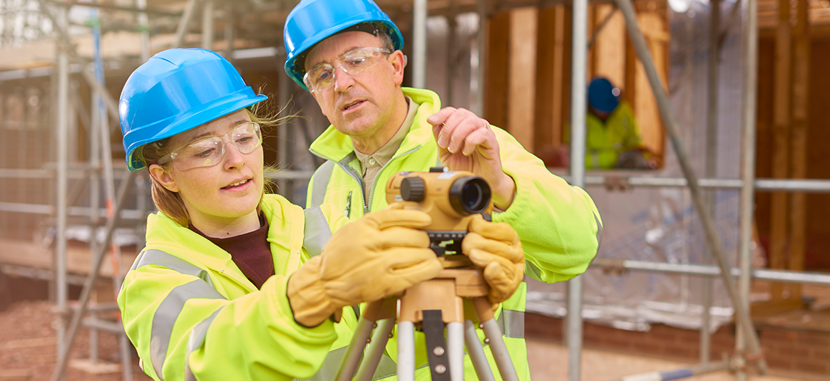 Two people working on site with a theodolite